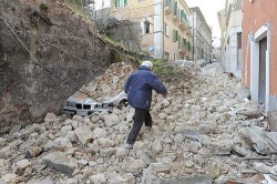 A man walks on debris as he looks for his relatives after an earthquake, in downtown Aquila